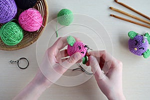 Making colored crochet bird. Toy for babies or trinket.  On the table threads, needles, hook, cotton yarn. Handmade gift. DIY