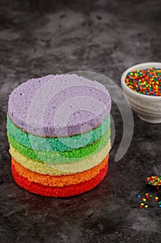 Making colorful rainbow birthday cake with sugar sprinkles