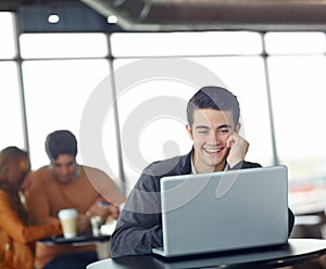 Making connections online. A handsome young man using his laptop in a coffee shop.