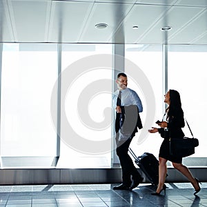 Making conversation on the way to departures. two businesspeople talking together while walking through an airport.