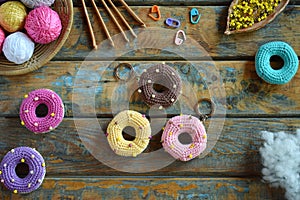 Making crochet amigurumi donuts. Toy for babies or trinket.  On the table threads, needles, hook, cotton yarn. Handmade gift.