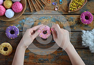 Making crochet amigurumi donuts. Toy for babies or trinket.  On the table threads, needles, hook, cotton yarn. Handmade gift.