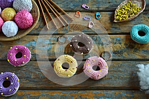 Making crochet amigurumi donuts. Toy for babies or trinket.  On the table threads, needles, hook, cotton yarn. Handmade gift.