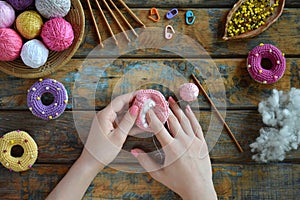 Making crochet amigurumi donuts. Toy for babies or trinket.  On the table threads, needles, hook, cotton yarn. Handmade gift. DIY