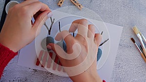 Making Diy Merry Christmas deer on greeting card postcard made of pebbles, sea stones, clothespins and branches on white