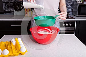 Making dough for Easter cake at home in the kitchen. Flour is poured out and sifted through a green sieve in female hands into a