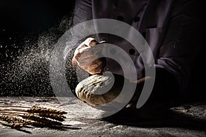 Making dough by hands at bakery or at home. Flour cloud in the air. Close up of chef hands preparing for kneading the dough on the