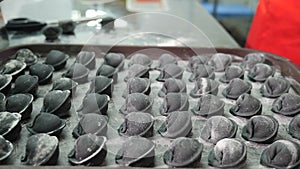 Making dumpling in modern foodstuff manufacturing. Chef hands putting ready dumplings of black color on tray. Homemade