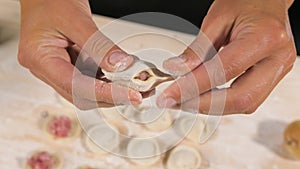 Making dumplings. Chef hands forming small handmade ravioli on kitchen table.