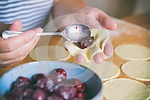 Making dumplings filled with sour cherry with sugar