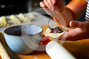 Making dumplings filled with sour cherry with sugar