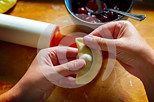 Making dumplings filled with sour cherry with sugar