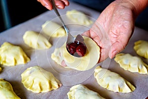 Making dumplings filled with sour cherry with sugar