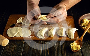 Making dumplings at home. Close-up of a man hands making dumplings from dough