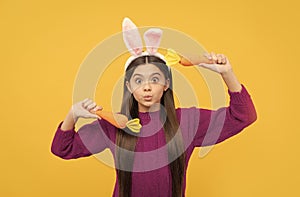 making faces. funny child in hare ears hold carrot. teenager girl wear rabbit costume