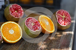 Making of fresh juice. Green ripe pomegranates and oranges on the table. Sliced fruits. Healthy organic products.