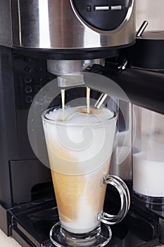 Making glass of coffee latte in carob coffee machine