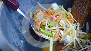 Making of green papaya salad with ingredients crab dried shrimp are mixing and pounding in a mortar.