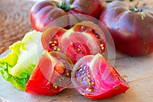 Making green salad with big ripe raddish-purple heirloom tomatoes Black Crimea