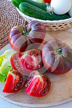 Making green salad with big ripe raddish-purple heirloom tomatoes Black Crimea