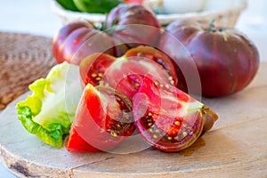 Making green salad with big ripe raddish-purple heirloom tomatoes Black Crimea