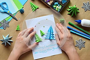 Making greeting card with origami 3D Xmas tree from paper. Merry Christmas and Happy New Year decoration. Childrens DIY concept.