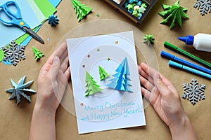 Making greeting card with origami 3D Xmas tree from paper. Merry Christmas and Happy New Year decoration. Childrens DIY concept.