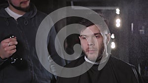 Making haircut look perfect. Young bearded man getting haircut by hairdresser while sitting in chair at barbershop