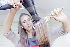 Making hairstyle using hair dryer. girl with blond long hair in a beauty salon
