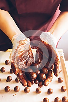 Making handmade chocolates. Round chocolates doused with liquid chocolate in the hands of the confectioner chocolatier.