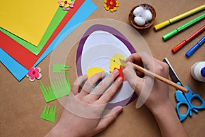 Making of handmade Easter decoration. Child made greeting card in egg shape. Childrens DIY concept, gift with your own hands.