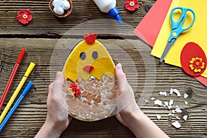 Making of handmade Easter decoration. Child made greeting card from eggshell. Childrens DIY concept, gift with your own hands.