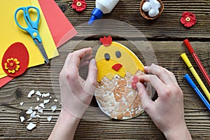 Making of handmade Easter decoration. Child made greeting card from eggshell. Childrens DIY concept, gift with your own hands.