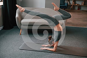 Making handstand. Young woman in yoga clothes doing fitness indoors