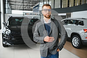 Making his choice. Horizontal portrait of a young man in a suit looking at the car and thinking if he should buy it