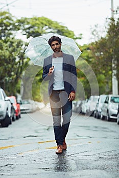Making his way in the rain. Full length shot of a handsome young businessman on his morning commute in the rain.