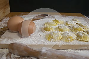 Making homemade Ravioli / Tortellini /dumpling with eggs on floured wood