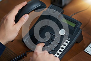 Making that important call. an unrecognizable man dialling a number on a telephone. photo