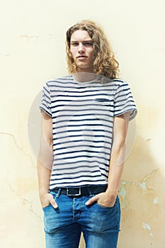 Making indie style his own. Young man with long ,curly hair and a casual sense of style.