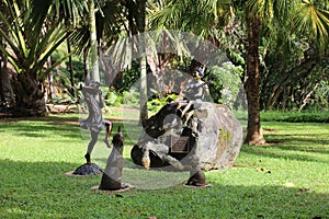 Making Joyful Noise, bronze sculptures of a boy playing a guitar, a girl playing a flute and two dogs on a grassy area in Kauai