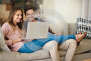Making light work of the monthly budget. a happy young couple using a laptop together while relaxing on the sofa at home