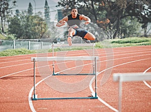 Making it look easy. Full length shot of a handsome young male athlete practicing hurdles on an outdoor track.