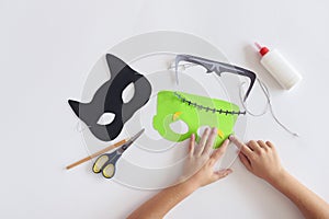 Making masks paper holiday Halloween Monster`s mask Black cat Hands top view