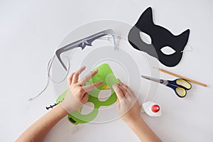 Making masks paper holiday Halloween Monster`s mask Black cat Hands top view