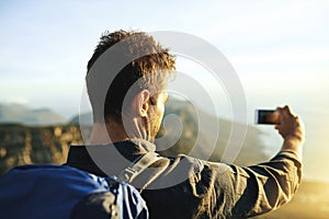 Making memories is the best part. a young man taking selfies while hiking up a mountain.