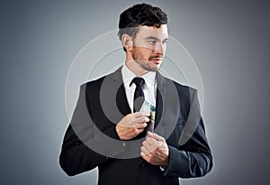 Making money without morals. Studio shot of a young businessman concealing money in his jacket against a gray background