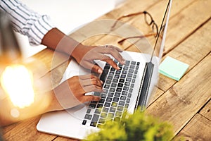 Making money is not that hard anymore. Cropped shot of an unrecognizable young woman using her laptop on a wooden table.