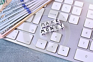 Making money online concept with computer keypad, dollar bills and cubes with text.