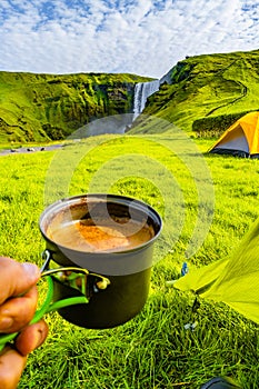 Making morning coffee in front of Skogarfoss waterfall, while hi