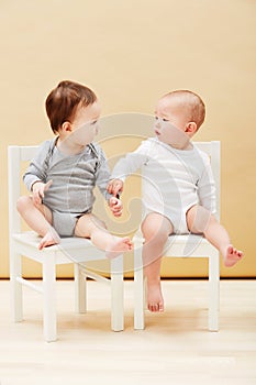 Making new friends. Adorable shot of two cute babies sitting on chairs and smiling at each other.